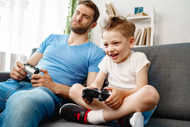 Father and his little son playing video games together at home - Фото, зображення