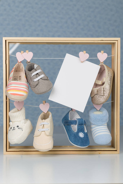 Комплект детской обуви в деревянной рамке с серым фоном плюс поздравительная открытка - Фото, изображение