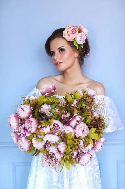 Beautiful woman with bouquet wearing white dress - Photo, Image