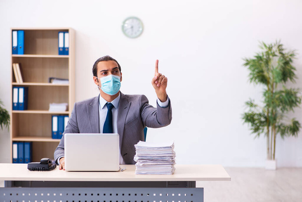 Junge männliche Mitarbeiter tragen bei Pandemie Maske - Foto, Bild
