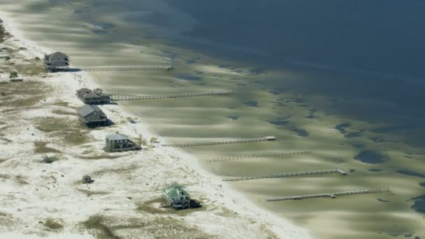 Vue aérienne de maisons en bois sur pilotis avec jetée sur une plage de sable blanc pélicans reposant au soleil Golfe du Mexique Floride Panhandle Amérique   - Séquence, vidéo