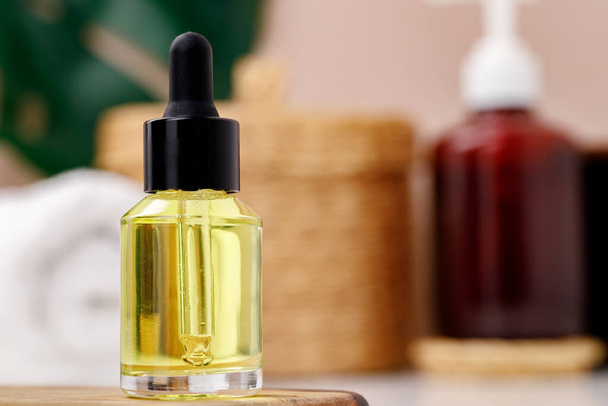 Bottle of yellow cosmetic oil on wooden tray close up - Foto, imagen
