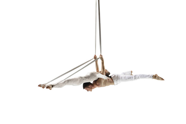 Couple of young acrobats, circus athletes isolated on white studio background. Training perfect balanced in flight - Valokuva, kuva
