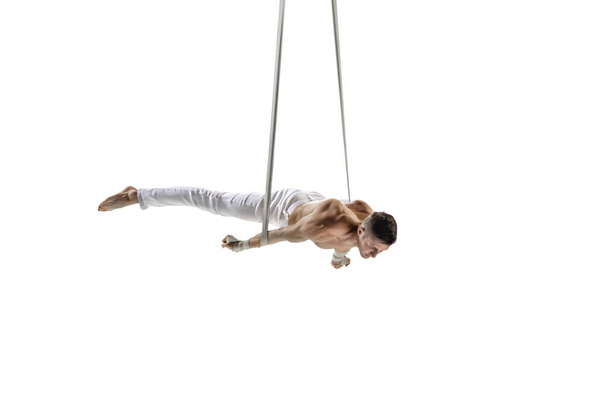 Young male acrobat, circus athlete isolated on white studio background. Training perfect balanced in flight - Photo, Image