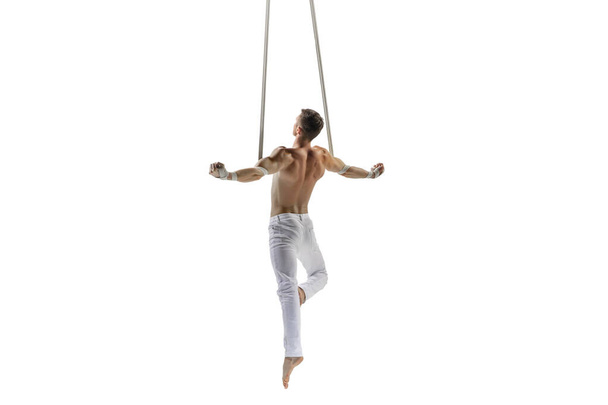 Young male acrobat, circus athlete isolated on white studio background. Training perfect balanced in flight - Foto, Imagen