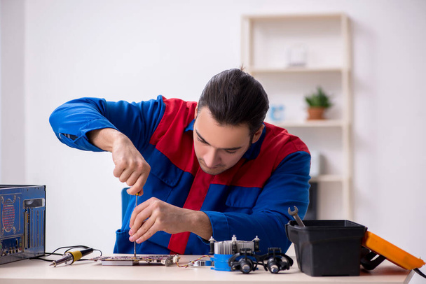 Молодий чоловік ремонтує комп'ютер
 - Фото, зображення