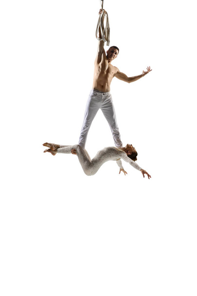 Couple of young acrobats, circus athletes isolated on white studio background. Training perfect balanced in flight - Фото, зображення