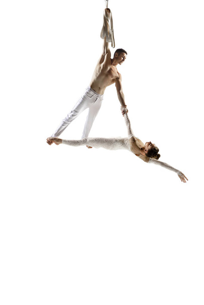 Couple of young acrobats, circus athletes isolated on white studio background. Training perfect balanced in flight - Valokuva, kuva
