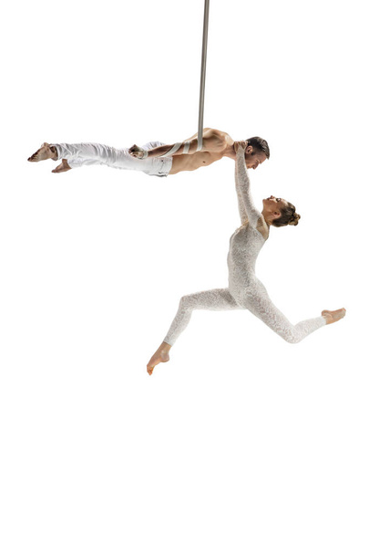 Couple of young acrobats, circus athletes isolated on white studio background. Training perfect balanced in flight - Foto, afbeelding
