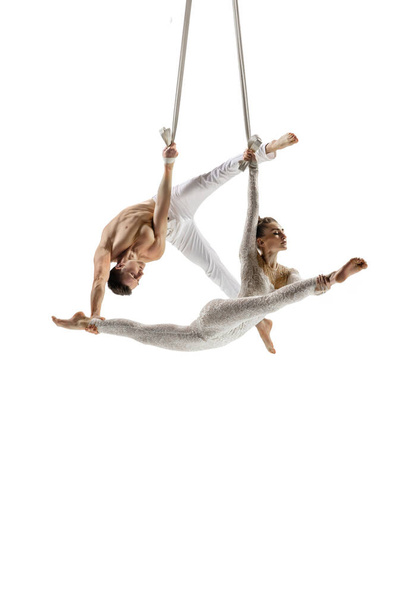 Couple of young acrobats, circus athletes isolated on white studio background. Training perfect balanced in flight - Foto, imagen
