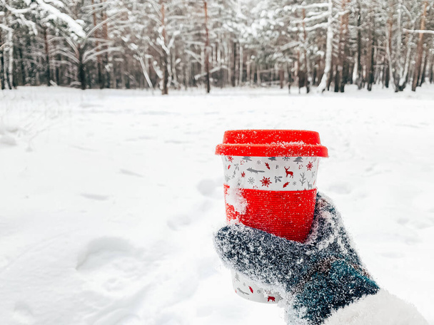 Havas téli háttér, piros üveg egy ital a kézben - Fotó, kép