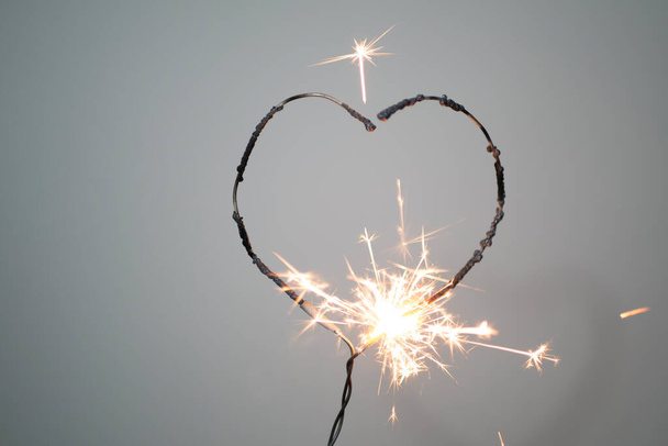 Forma do coração sparklerburning em um fundo cinza com conceito de fundo valentine. - Foto, Imagem