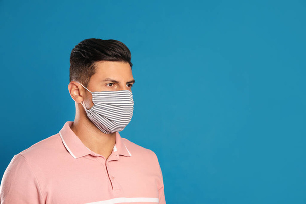 Man in protective face mask on blue background. Space for text - Foto, Imagem