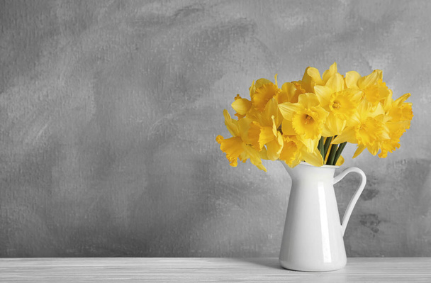 Color of the year 2021. Bouquet of yellow daffodils on table against grey background, space for text - Valokuva, kuva