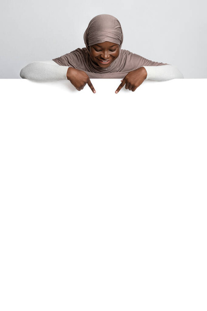 Смотри. Африканская мусульманка в хиджабе указывает на белую рекламную доску - Фото, изображение
