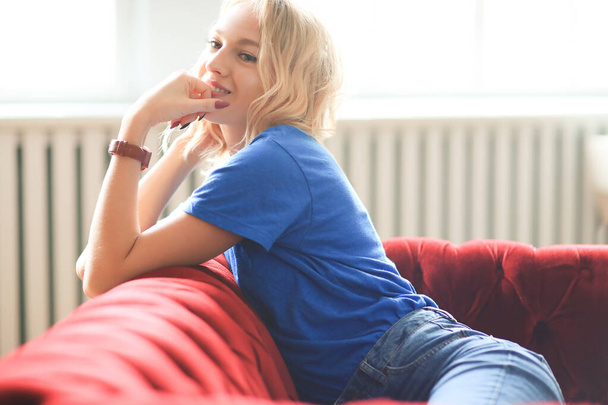 Young girl on a red sofa - Valokuva, kuva