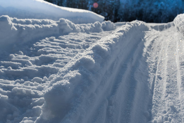深い雪の中でスノーモービルのトラック。雪に覆われたフィールドを横断するスノーモービルのねじれ痕跡 - 写真・画像