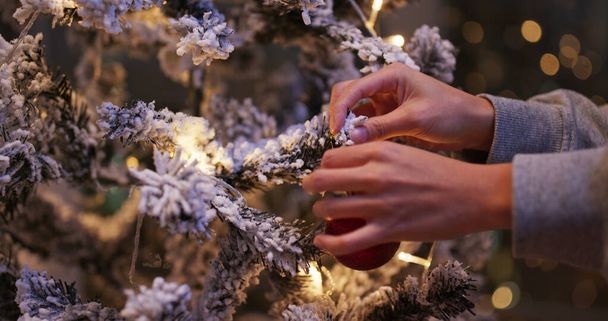 Femme a mis une décoration de Noël sur l'arbre à la maison - Photo, image