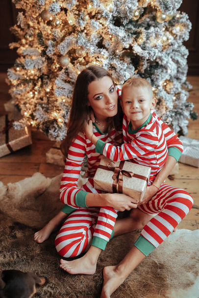 Молода мати та її син у святкових піжамах під час різдвяної події
 - Фото, зображення