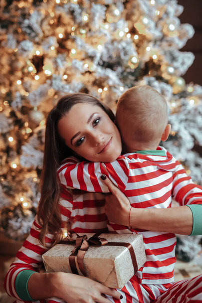 Joven madre y su hijo en pijama festivo durante el evento de Navidad
 - Foto, imagen