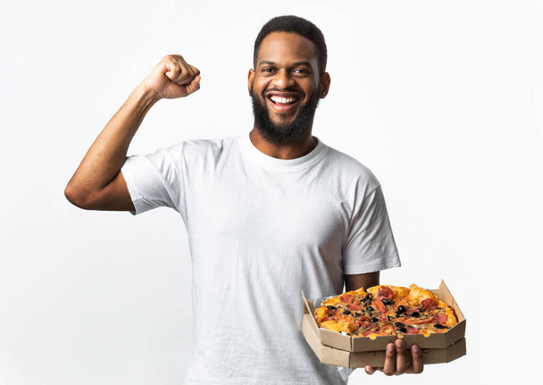 Africain Guy posant avec boîte à pizza montrant des biceps, fond blanc - Photo, image