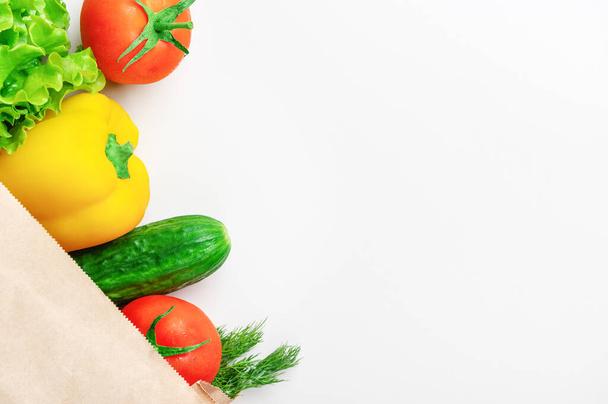 Beyaz arka planda sarı biber, salatalık, domates ve yeşilliklerin üst görüntüsü. Çevre dostu ürünler. Sağ tarafta boş kopyalama alanı. Flatlay stili. Sağlıklı yiyecekler ve diyet konsepti - Fotoğraf, Görsel