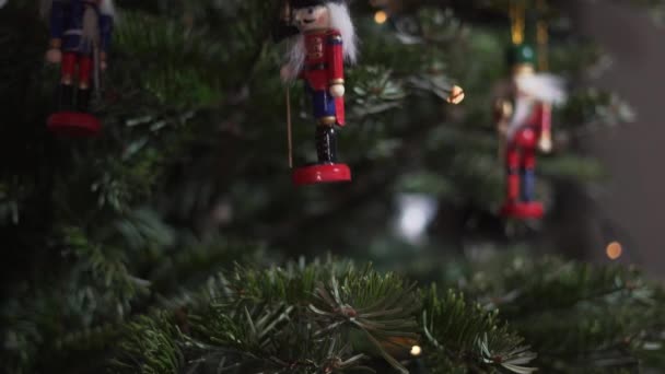 Decoración Juguete Cascanueces en el árbol de Navidad. 4K Dolly Slider Shot. Soldado cascanueces en un árbol de Navidad con fondo borroso. Hermoso árbol de Navidad decorado, el juguete cascanueces, luces de hadas. - Imágenes, Vídeo