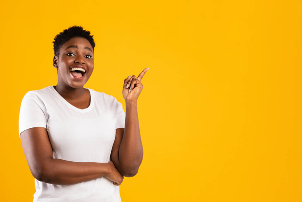gai africaine femme pointant doigt vers le haut ayant idée, fond jaune - Photo, image