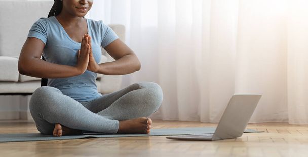 Yoga çevrimiçi. Tanımlanamayan Afrikalı Kadın evde dizüstü bilgisayarla meditasyon yapıyor. - Fotoğraf, Görsel