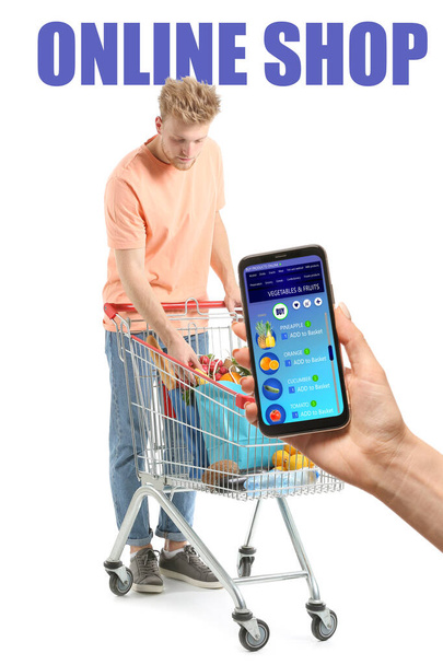 Женщина держит мобильный телефон с открытой страницей службы доставки еды и молодой человек с корзиной покупок на белом фоне - Фото, изображение