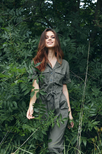 Portrait of a woman beautiful smiling jumpsuit near the green leaves nature  - Zdjęcie, obraz