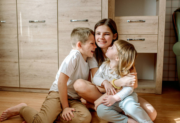 three children play at home. brother and sisters laugh and have fun. Homeliness is admiration and love. Family concept. - Photo, image