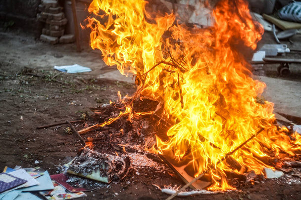 Bücher und Notizbücher brennen vor dem Hintergrund eines zerstörten Gebäudes - Foto, Bild