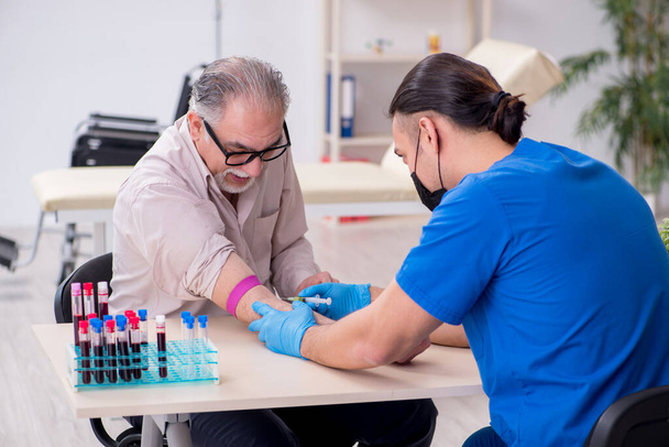 Alte Patientin besucht jungen männlichen Arzt bei Bluttransfusion - Foto, Bild