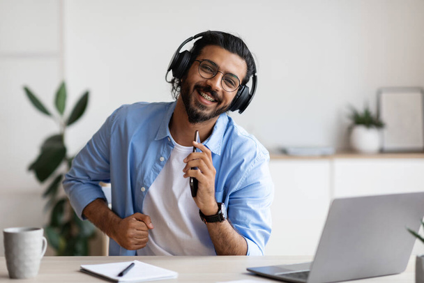 Wesoły Arab Guy w słuchawkach bezprzewodowych Słuchanie muzyki na smartfonie i śpiew - Zdjęcie, obraz