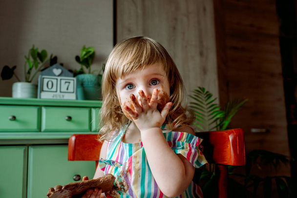 Smeared baby eating chocolate for the first time. Chocolate Day July 7th - Fotoğraf, Görsel