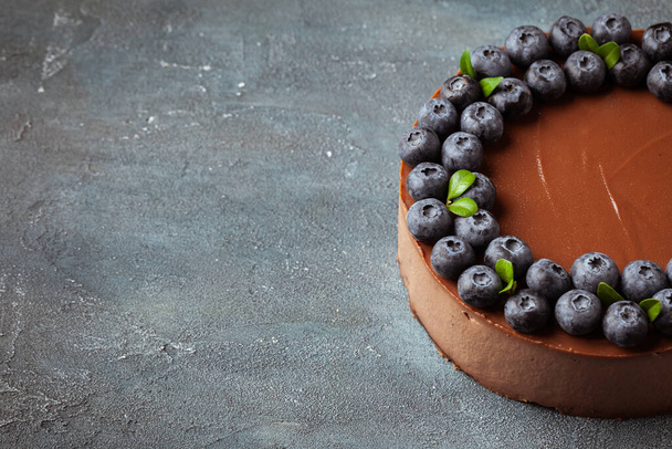 Chocolate brown cheesecake with fresh blueberries on vintage concrete background. - Fotografie, Obrázek