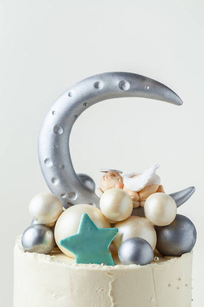 Christening cake with little baby angel sleeping on top. Bunk cake for newborn celebration with the silver moon and spheres made of chocolate decoration - Foto, Bild