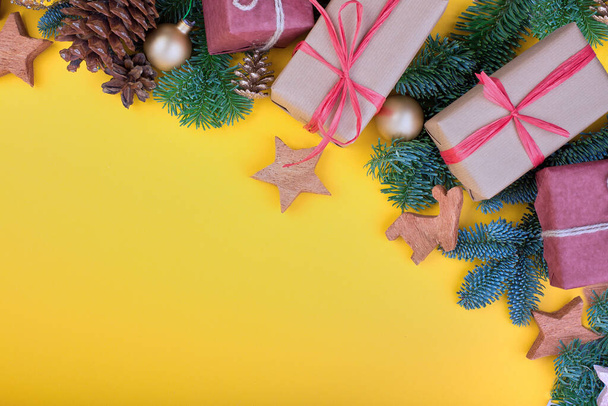 Fichtenzweig, Zapfen und Vintage-Spielzeugdekoration an Weihnachten oder Neujahr auf gelbem Hintergrund. - Foto, Bild