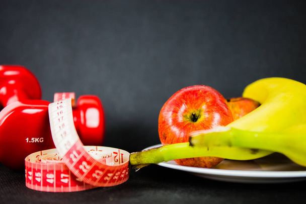 Programa para la pérdida de peso con bajas calorías y ejercicio diario. Reducción del tamaño de la dieta y la cintura con un entrenamiento saludable de frutas y mancuernas - Foto, Imagen