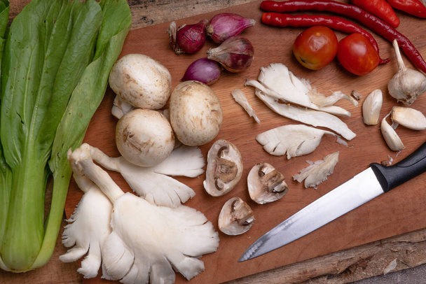 ready to cook. mushrooms, chilies, garlic and shallots on a wooden cutting board - Photo, Image