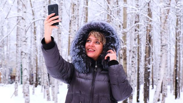 Woman uses a mobile phone on a winter day, close-up - Фото, зображення