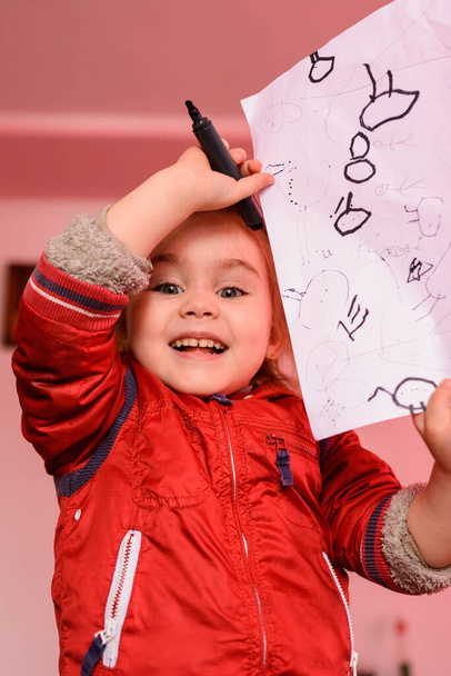 Fille d'âge préscolaire apprend à dessiner un cercle, cercles noirs sur une feuille blanche de papier, enfant heureux. 2020 - Photo, image