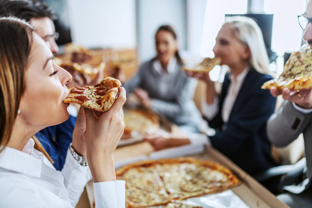 Group of white collar workers having lunch break.They are hungry and enjoying pizza. - Zdjęcie, obraz