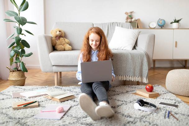 Dziewczyna siedząca na podłodze, używająca laptopa, pisząca na klawiaturze - Zdjęcie, obraz