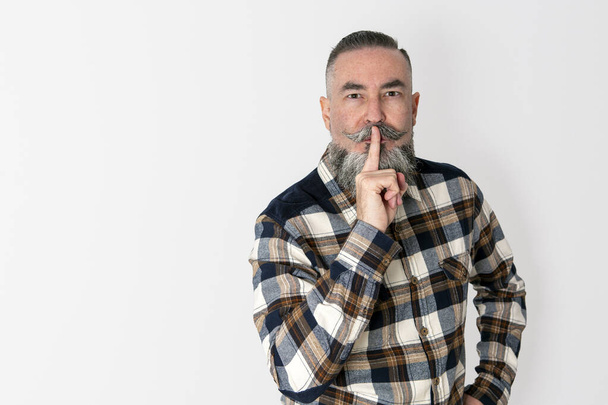 hipster with wide beard, retro style plaid shirt, on white background. She puts her index finger to the corner of her lips making the gesture of ordering silence, concept of silence - Фото, изображение