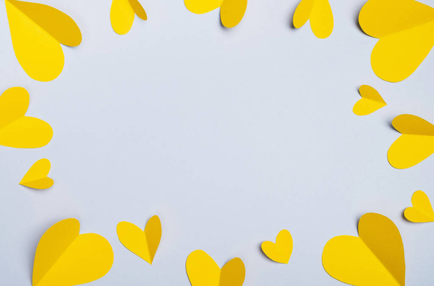 Día de San Valentín. Corazones amarillos hechos de papel sobre fondo gris. Composición mínima en colores de moda. Vista superior, plano, espacio para copiar, marco - Foto, Imagen