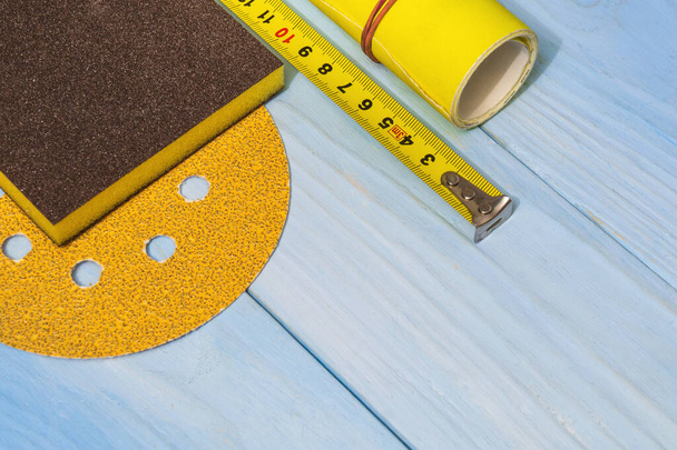 Set of abrasive tool and yellow sandpaper on blue wooden board - Photo, Image