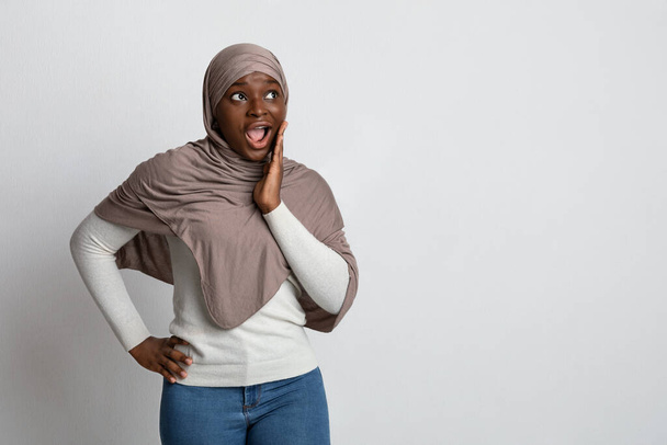 Schockierendes Angebot. Überraschte schwarze islamische Dame im Hidschab berührt vor Aufregung Gesicht - Foto, Bild