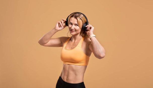 Lockdown, activity, wellness, lifestyle and motivation. Beautiful smiling muscular middle aged lady in sports uniform - Photo, Image